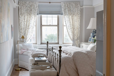 Elegant medium tone wood floor and brown floor bedroom photo in New York with white walls