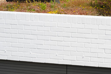 Idée de décoration pour une façade de maison blanche design en brique de plain-pied avec un toit plat.