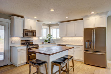 Inspiration for a large contemporary l-shaped light wood floor kitchen remodel in Las Vegas with a double-bowl sink, shaker cabinets, white cabinets, granite countertops, stainless steel appliances and an island