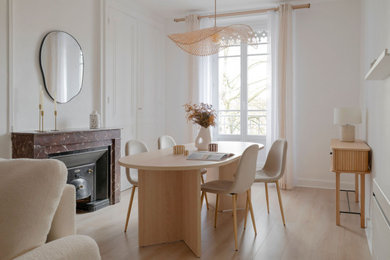 Cette image montre une salle à manger nordique de taille moyenne avec un mur blanc, sol en stratifié, une cheminée standard, un manteau de cheminée en pierre et un sol beige.