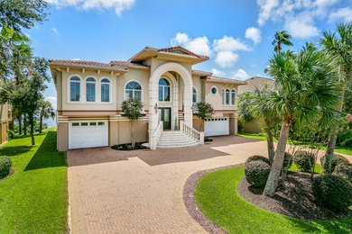 Inspiration for a huge contemporary beige two-story stucco house exterior remodel in Other with a hip roof and a tile roof