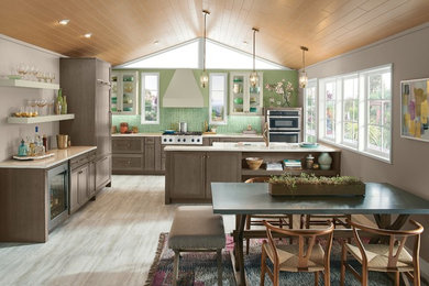 Design ideas for a mid-sized country l-shaped eat-in kitchen in Detroit with recessed-panel cabinets, dark wood cabinets, quartz benchtops, green splashback, glass sheet splashback, stainless steel appliances, a peninsula, brown floor and white benchtop.