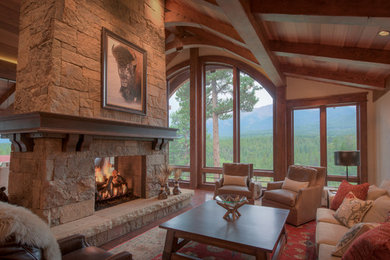Inspiration for a rustic open concept living room remodel in Denver with a two-sided fireplace and a stone fireplace