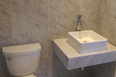 Inspiration for a mid-sized modern 3/4 gray tile, white tile and porcelain tile marble floor bathroom remodel in New York with a one-piece toilet, beige walls, a vessel sink and marble countertops