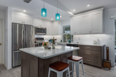 This is an example of a small transitional l-shaped eat-in kitchen in Other with a farmhouse sink, shaker cabinets, white cabinets, quartz benchtops, stainless steel appliances, vinyl floors, with island and grey floor.