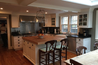 Design ideas for a mid-sized country l-shaped open plan kitchen in New York with a farmhouse sink, shaker cabinets, white cabinets, wood benchtops, grey splashback, stainless steel appliances, medium hardwood floors, with island and brown floor.