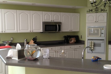 Example of a large transitional medium tone wood floor kitchen design in Jacksonville with a farmhouse sink, shaker cabinets, white cabinets, quartzite countertops, white backsplash, ceramic backsplash, stainless steel appliances and an island