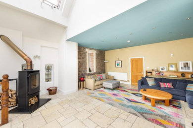 Cette image montre un salon design avec un mur beige, un sol en travertin, un poêle à bois et un sol beige.
