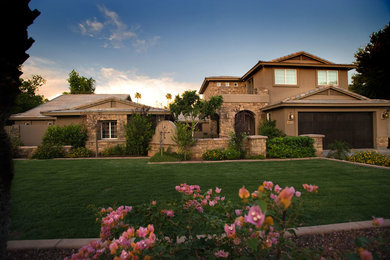 Inspiration for a large timeless beige two-story stone house exterior remodel in Phoenix with a hip roof and a shingle roof