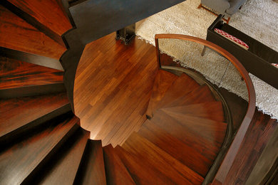 Example of a huge minimalist wooden curved mixed material railing staircase design in New York with wooden risers