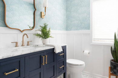 Example of a mid-sized transitional marble floor, gray floor and wallpaper powder room design in Chicago with shaker cabinets, blue cabinets, blue walls, an undermount sink, marble countertops, white countertops and a freestanding vanity