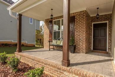 This is an example of a mid-sized traditional stamped concrete front porch design in Atlanta with a roof extension.