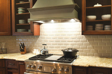 Large elegant medium tone wood floor kitchen photo in Boston with recessed-panel cabinets, dark wood cabinets, granite countertops, white backsplash, subway tile backsplash and stainless steel appliances