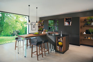 Offene, Geräumige Moderne Küche mit Einbauwaschbecken, flächenbündigen Schrankfronten, schwarzen Schränken, Laminat-Arbeitsplatte, Küchenrückwand in Weiß, Rückwand aus Stein, Küchengeräten aus Edelstahl, Linoleum, Kücheninsel und beigem Boden in Hannover