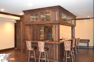 Inspiration for a huge rustic l-shaped medium tone wood floor seated home bar remodel in Denver with raised-panel cabinets, medium tone wood cabinets, granite countertops, multicolored backsplash and stone slab backsplash
