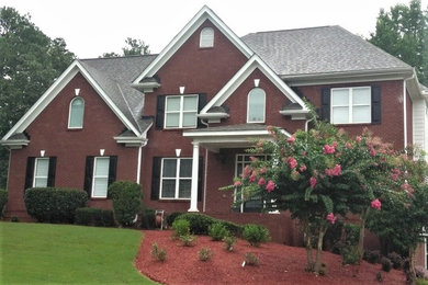 This is an example of a large traditional two-storey brick red house exterior in Atlanta with a hip roof and a shingle roof.