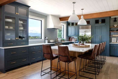 Inspiration for a mid-sized contemporary l-shaped medium tone wood floor enclosed kitchen remodel in Seattle with an undermount sink, shaker cabinets, blue cabinets, quartz countertops, stainless steel appliances, an island and white countertops