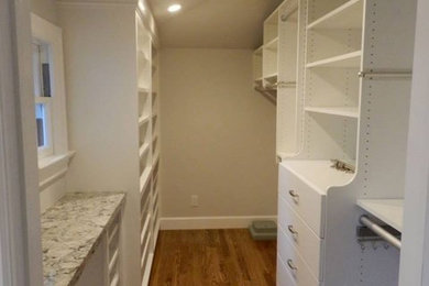 Example of a mid-sized trendy gender-neutral medium tone wood floor walk-in closet design in San Francisco with flat-panel cabinets and white cabinets