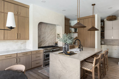 Inspiration for a transitional l-shaped medium tone wood floor and brown floor kitchen remodel in Phoenix with an undermount sink, shaker cabinets, medium tone wood cabinets, gray backsplash, stone slab backsplash, stainless steel appliances, an island and gray countertops