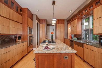 Eat-in kitchen - contemporary galley eat-in kitchen idea in Seattle with a farmhouse sink, flat-panel cabinets, medium tone wood cabinets, granite countertops, metallic backsplash, ceramic backsplash and stainless steel appliances