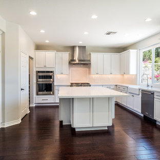 Idéer för ett mellanstort klassiskt vit kök, med en rustik diskho, skåp i shakerstil, vita skåp, bänkskiva i kvarts, vitt stänkskydd, stänkskydd i porslinskakel, rostfria vitvaror, korkgolv och en köksö