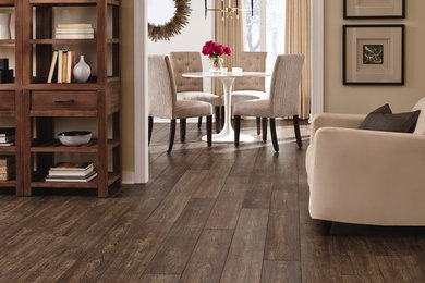 Example of a mid-sized minimalist open concept laminate floor and brown floor family room design in Boston with beige walls, no fireplace and a media wall