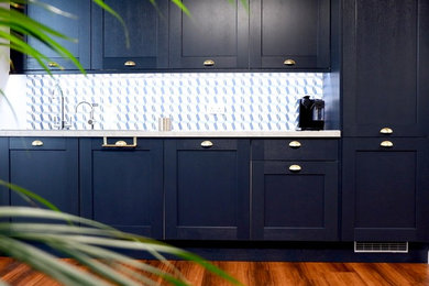 Small contemporary single-wall open plan kitchen in Manchester with a built-in sink, recessed-panel cabinets, blue cabinets, laminate countertops, blue splashback, cement tile splashback, integrated appliances, laminate floors, no island, brown floors and grey worktops.