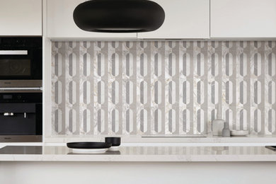 Minimalist galley eat-in kitchen photo in New York with flat-panel cabinets, beige cabinets, quartzite countertops, multicolored backsplash, porcelain backsplash, black appliances, an island and beige countertops