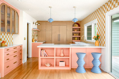 Inspiration for an eclectic l-shaped medium tone wood floor enclosed kitchen remodel in Portland with an undermount sink, flat-panel cabinets, pink cabinets, multicolored backsplash, ceramic backsplash, paneled appliances and white countertops