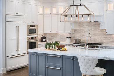 Example of a large transitional l-shaped medium tone wood floor and brown floor eat-in kitchen design in Boston with an undermount sink, recessed-panel cabinets, white cabinets, marble countertops, gray backsplash, ceramic backsplash, stainless steel appliances and an island