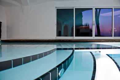 Esempio di una grande piscina coperta design personalizzata con piastrelle