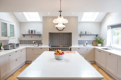 This is an example of a large scandinavian open plan kitchen in Oxfordshire with a drop-in sink, shaker cabinets, white cabinets, quartzite benchtops, white splashback, timber splashback, laminate floors, with island and beige floor.