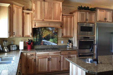 Mid-sized mountain style l-shaped porcelain tile and brown floor kitchen photo in Salt Lake City with shaker cabinets, medium tone wood cabinets, granite countertops, stainless steel appliances, an island, an undermount sink, beige backsplash, wood backsplash and multicolored countertops