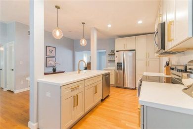 Mid-sized 1960s l-shaped light wood floor eat-in kitchen photo in Orlando with an integrated sink, shaker cabinets, gray cabinets, solid surface countertops, gray backsplash, marble backsplash, stainless steel appliances, an island and white countertops