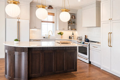 Example of a large classic l-shaped light wood floor and beige floor eat-in kitchen design in Montreal with an undermount sink, shaker cabinets, beige cabinets, quartzite countertops, white backsplash, ceramic backsplash, white appliances, an island and beige countertops