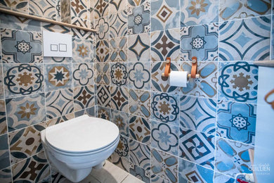 Réalisation d'un petit WC suspendu design avec des portes de placard blanches, un carrelage multicolore, un mur beige, un lavabo posé, un plan de toilette en bois et meuble-lavabo suspendu.