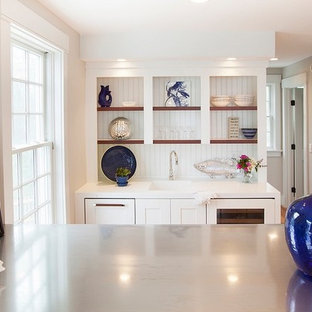 ポートランド(メイン)の小さいビーチスタイルのおしゃれなウェットバー (一体型シンク、シェーカースタイル扉のキャビネット、白いキャビネット、人工大理石カウンター、白いキッチンパネル、木材のキッチンパネル、淡色無垢フローリング) の写真