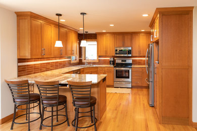 Kitchen - large southwestern u-shaped medium tone wood floor kitchen idea in Minneapolis with an undermount sink, flat-panel cabinets, granite countertops, ceramic backsplash, stainless steel appliances and an island