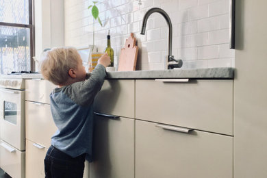 Inspiration for a small contemporary galley black floor kitchen remodel in New York with flat-panel cabinets, white cabinets, marble countertops, white backsplash, subway tile backsplash and gray countertops