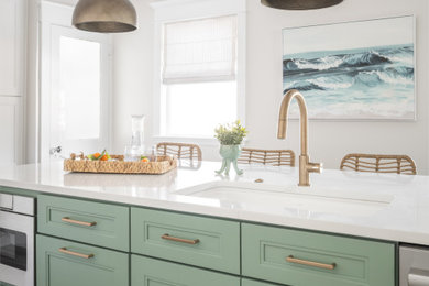 Bild på ett avskilt, stort maritimt vit vitt kök, med en undermonterad diskho, skåp i shakerstil, gröna skåp, bänkskiva i kvarts, vitt stänkskydd, stänkskydd i keramik, rostfria vitvaror, vinylgolv, en köksö och brunt golv