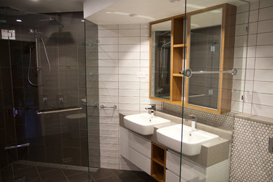 Mid-sized contemporary bathroom in Brisbane with white cabinets, a corner shower, white tile, ceramic tile, grey floor and a hinged shower door.