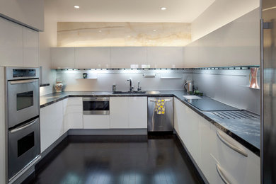 Example of a mid-sized minimalist u-shaped dark wood floor enclosed kitchen design in Houston with an undermount sink, flat-panel cabinets, white cabinets, marble countertops, white backsplash, metal backsplash, stainless steel appliances and an island