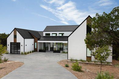 Large danish white two-story stucco exterior home photo in Austin with a metal roof and a black roof