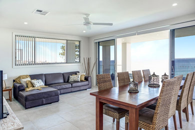 This is an example of a beach style living room in Wollongong with white walls, ceramic floors, a freestanding tv and brown floor.