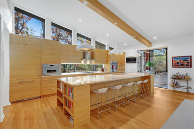 Inspiration for a 1950s galley medium tone wood floor, brown floor, exposed beam and vaulted ceiling kitchen remodel in Chicago with an undermount sink, flat-panel cabinets, medium tone wood cabinets, window backsplash, paneled appliances, an island and white countertops