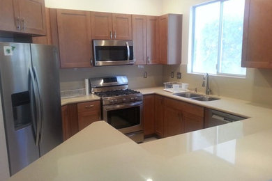 Inspiration for a small timeless kitchen remodel in Las Vegas with a double-bowl sink, shaker cabinets, medium tone wood cabinets, solid surface countertops, stainless steel appliances and no island