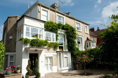 Photo of a large and white traditional brick semi-detached house in Surrey with three floors, a hip roof and a tiled roof.