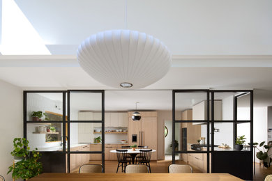 Example of a large 1950s u-shaped light wood floor and brown floor eat-in kitchen design in DC Metro with a drop-in sink, flat-panel cabinets, light wood cabinets, marble countertops, white backsplash, ceramic backsplash, black appliances and white countertops