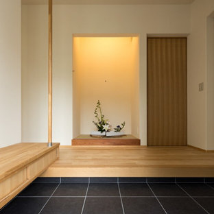 他の地域の中サイズの引き戸和風のおしゃれな玄関ホール (白い壁、磁器タイルの床、黒いドア、グレーの床) の写真