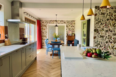 Design ideas for a medium sized midcentury kitchen in West Midlands with shaker cabinets, quartz worktops, white splashback, engineered quartz splashback, stainless steel appliances, an island, white worktops and a feature wall.